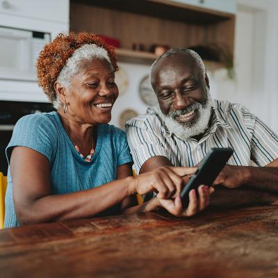 A senior couple looking at the same smart phone and smiling