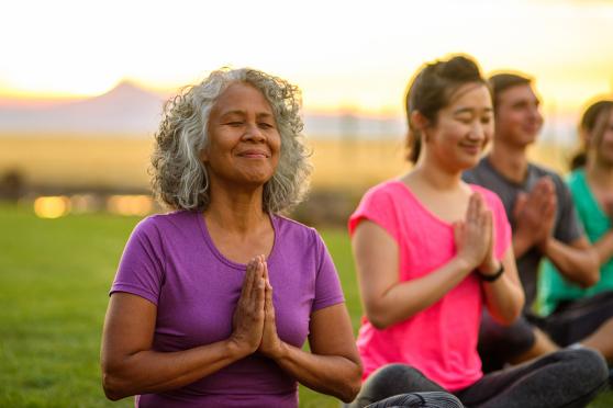 smiling mature woman in an outdoor group yoga class 