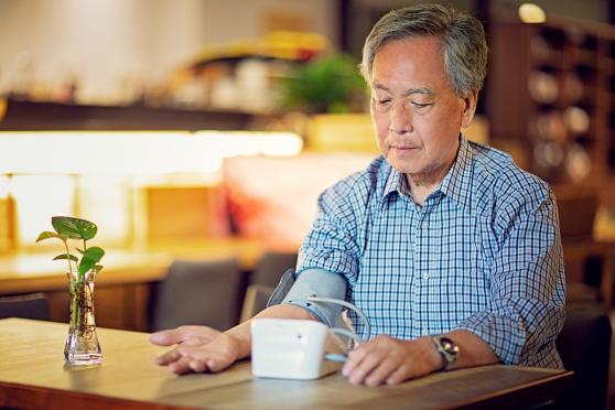 senior man checking his blood pressure at home